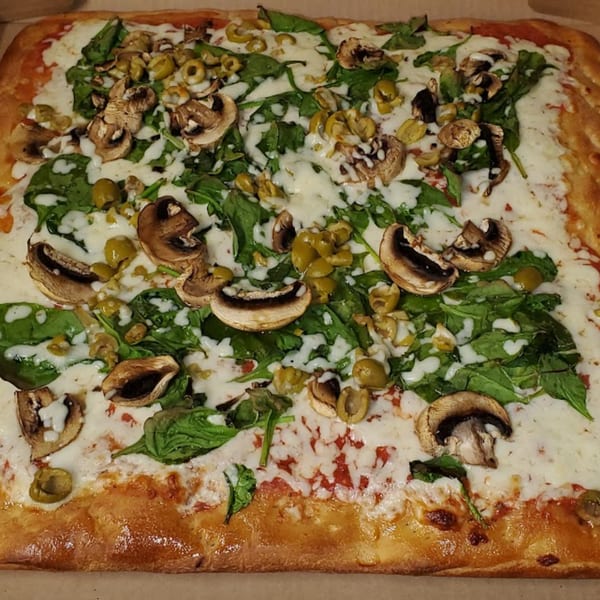 Town Center Pizzeria's rectangular pizza with spinach, mushrooms, olives, and melted cheese.