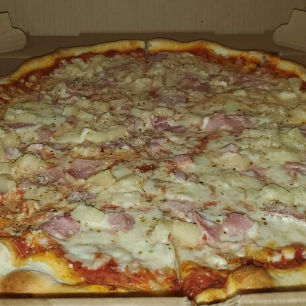 A close-up of a Hawaiian pizza from Town Center Pizzeria, with ham and pineapple toppings.