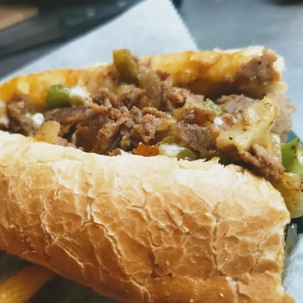 Close-up of a cheesesteak sandwich from Town Center Pizzeria, filled with meat, onions, and peppers.